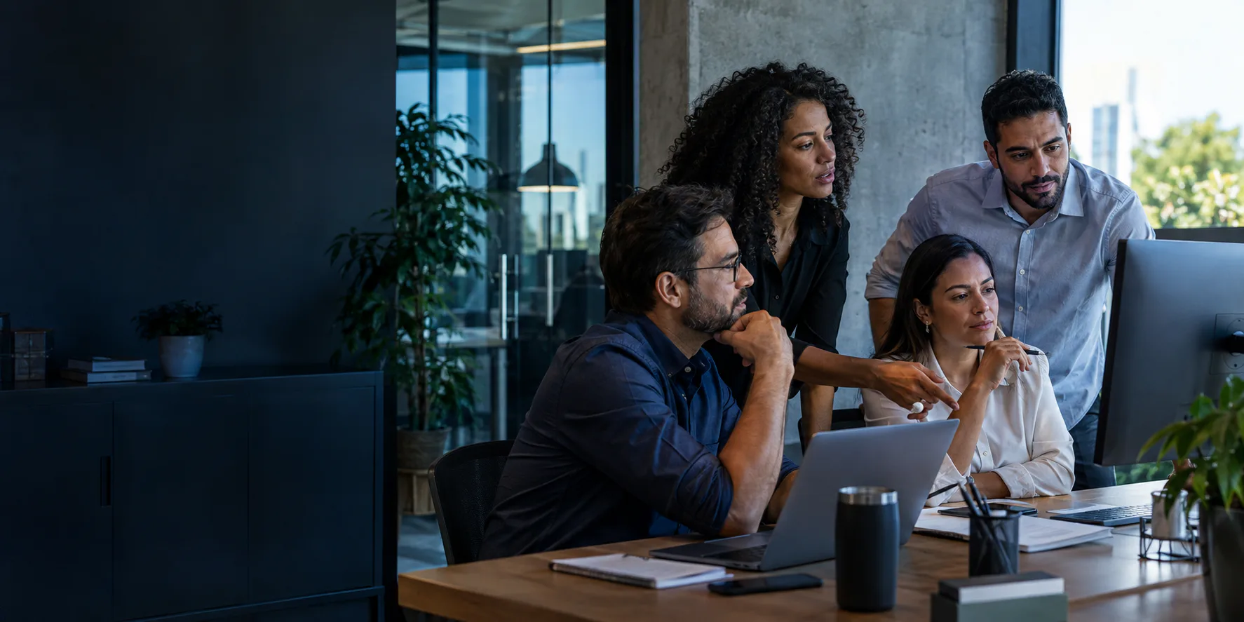 Equipe reunida analisando a operação da empresa em um computador